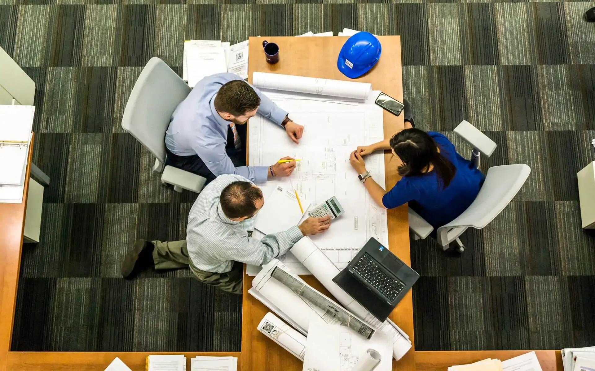 Equipo de trabajo revisando planos y documentación sobre una mesa de reuniones